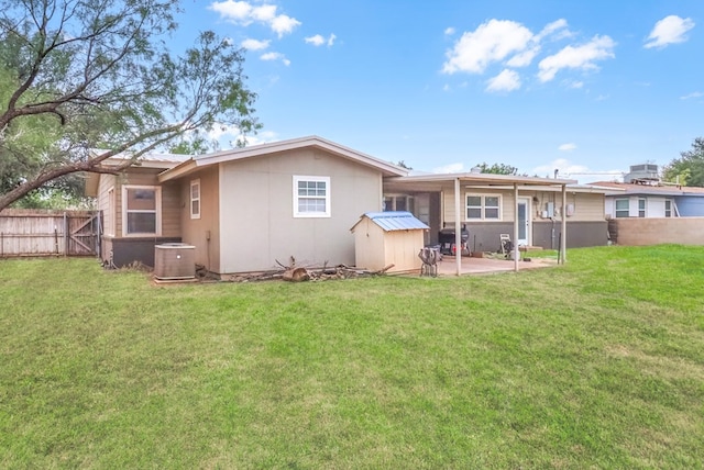 back of property featuring a patio, central air condition unit, a storage unit, and a lawn