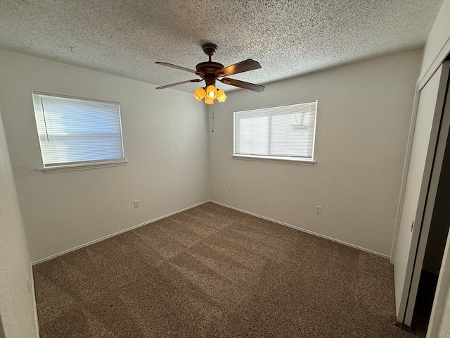 interior space featuring dark colored carpet, a textured ceiling, and ceiling fan