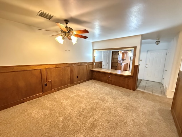 bonus room featuring wooden walls, ceiling fan, and light colored carpet