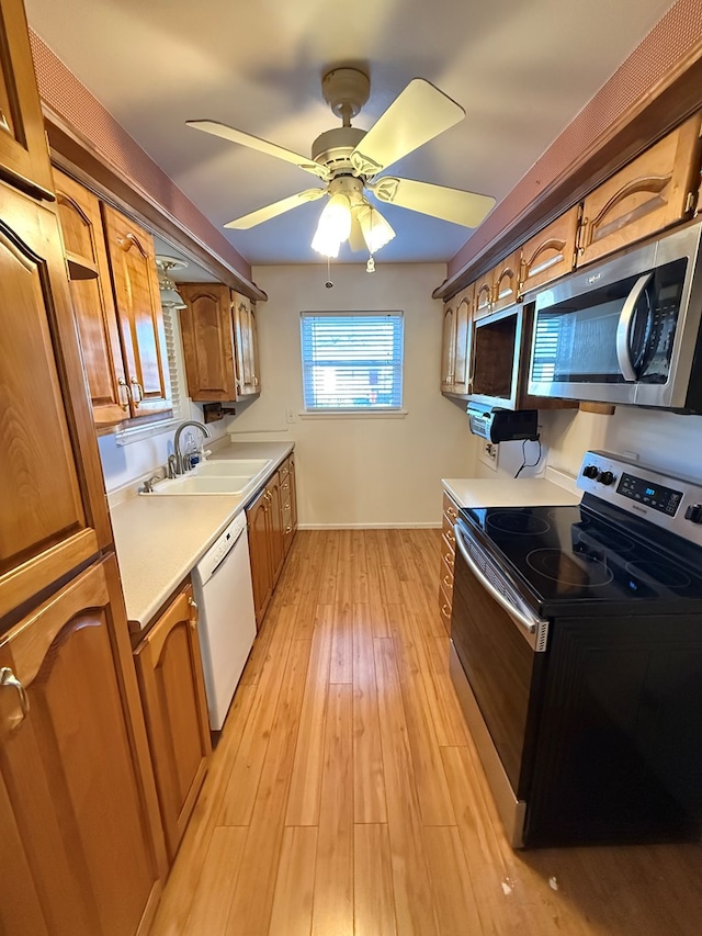 kitchen featuring appliances with stainless steel finishes, light hardwood / wood-style floors, ceiling fan, and sink