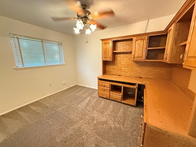 interior space featuring dark colored carpet, light brown cabinets, and ceiling fan