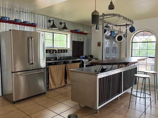 kitchen with plenty of natural light, light tile patterned floors, stainless steel appliances, and decorative light fixtures