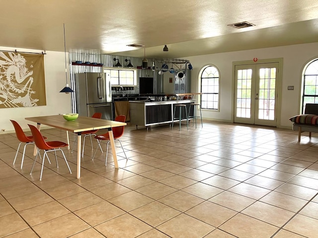 dining area with light tile patterned flooring, a textured ceiling, and french doors