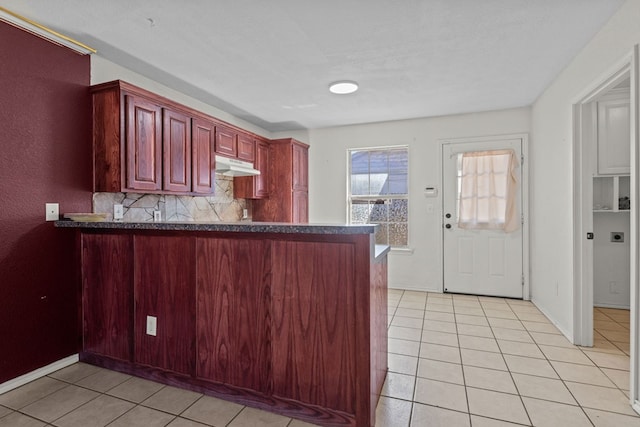 kitchen with light tile patterned floors, backsplash, and kitchen peninsula