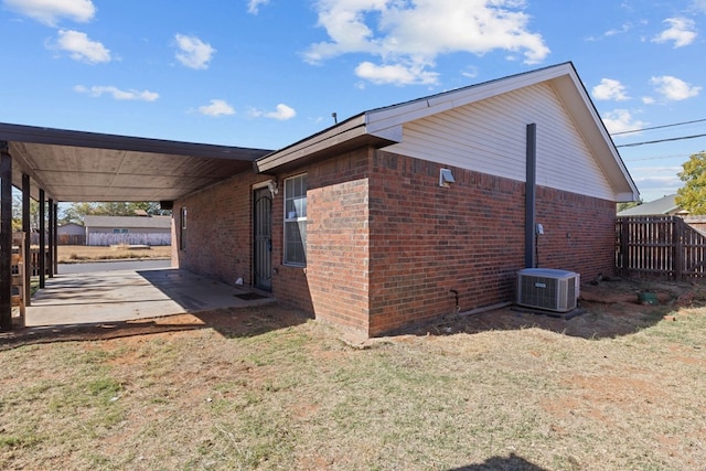 view of side of home featuring central AC and a yard