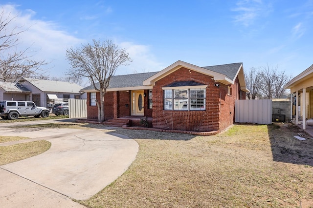 view of front of house featuring brick siding, a shingled roof, and fence