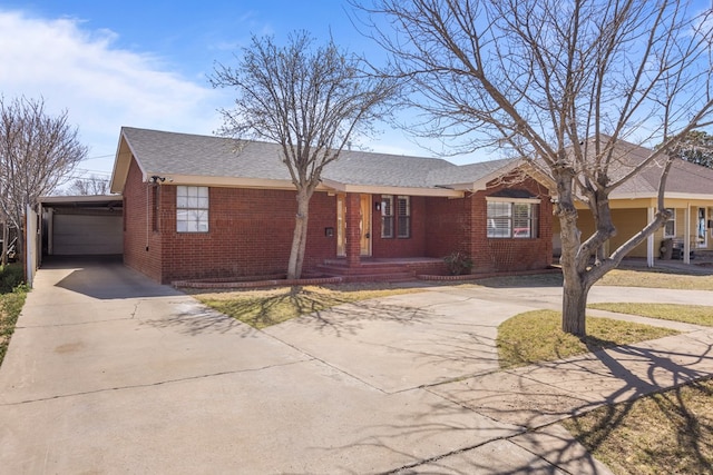 ranch-style home with concrete driveway, brick siding, and roof with shingles