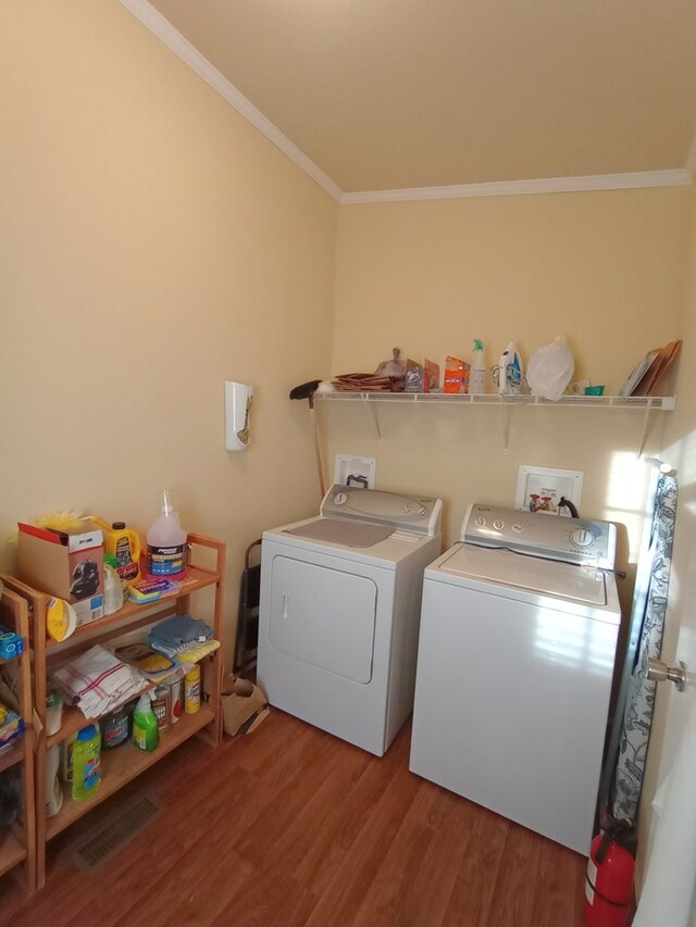 laundry room with hardwood / wood-style flooring, ornamental molding, and washing machine and clothes dryer