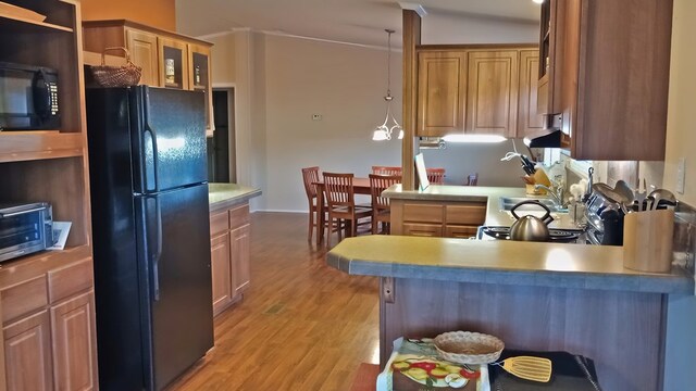 kitchen with pendant lighting, black appliances, vaulted ceiling, light wood-type flooring, and kitchen peninsula