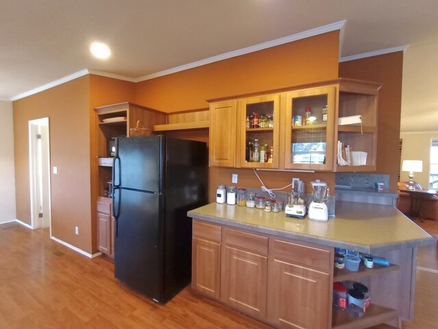 kitchen featuring light wood-type flooring, black fridge, and ornamental molding