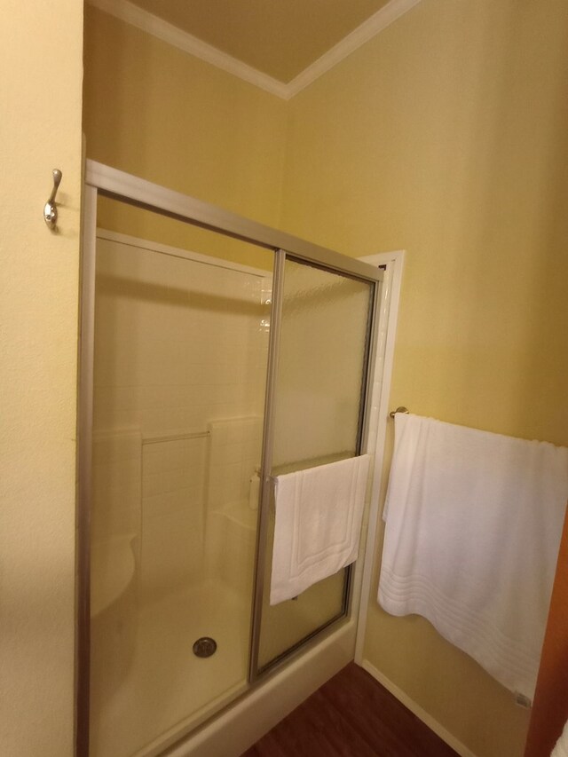 bathroom with hardwood / wood-style flooring, a shower with door, and crown molding