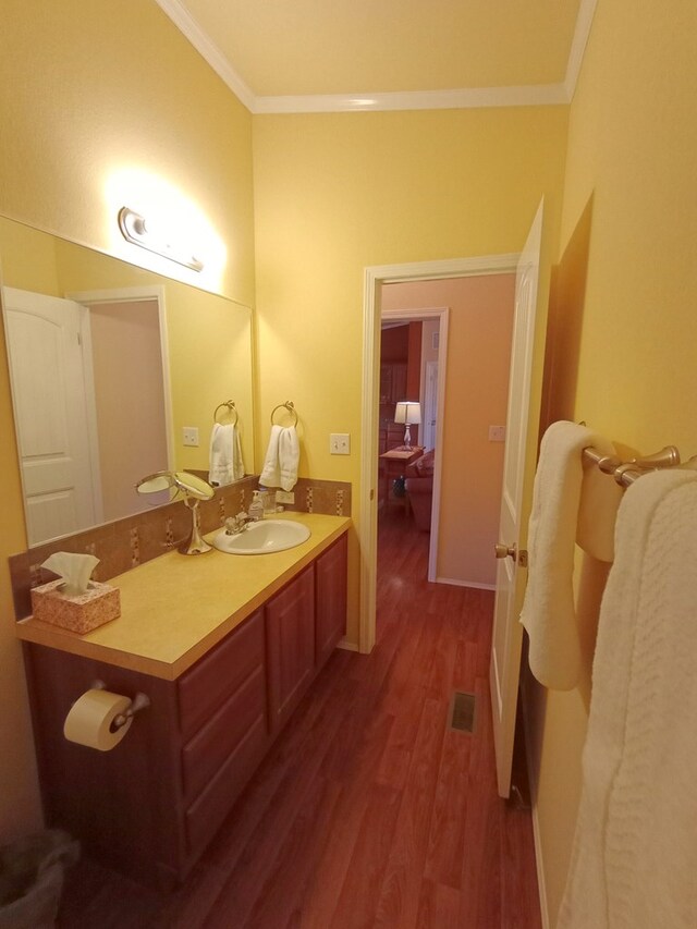 bathroom with crown molding, vanity, and wood-type flooring