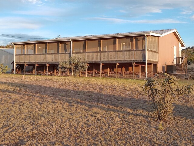 rear view of property with central air condition unit and a sunroom