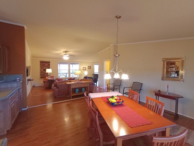 dining room featuring ornamental molding, ceiling fan with notable chandelier, dark hardwood / wood-style floors, and lofted ceiling