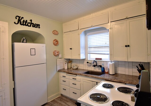 kitchen featuring backsplash, sink, white cabinets, and white appliances