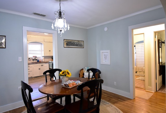 dining area featuring a chandelier, crown molding, and light hardwood / wood-style flooring