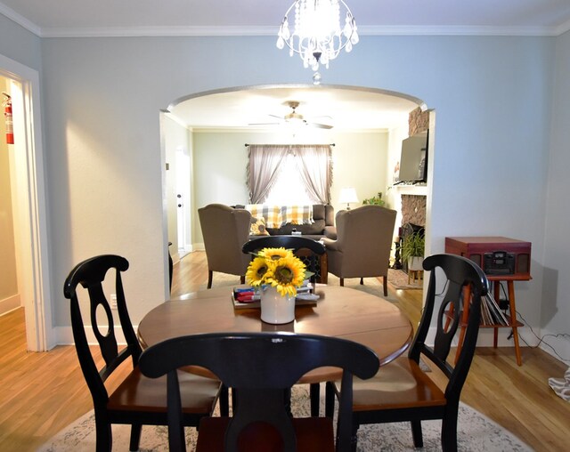 dining space featuring ceiling fan with notable chandelier, light wood-type flooring, and ornamental molding