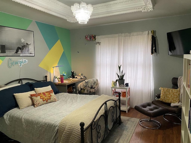 bedroom with ornamental molding, hardwood / wood-style floors, a notable chandelier, and a raised ceiling