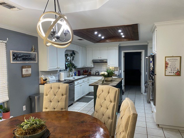 kitchen featuring stainless steel dishwasher, white cabinets, crown molding, and light tile patterned flooring