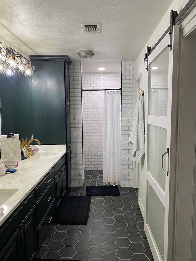 bathroom with vanity, curtained shower, a textured ceiling, and tile patterned flooring