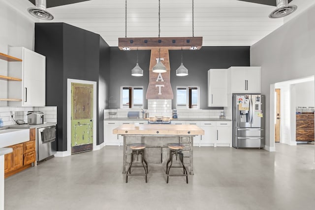 kitchen with white cabinets, decorative backsplash, stainless steel appliances, and hanging light fixtures