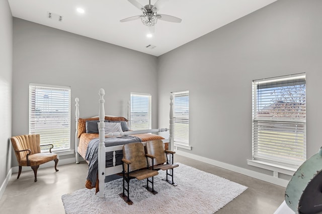 bedroom with concrete flooring, a towering ceiling, and ceiling fan