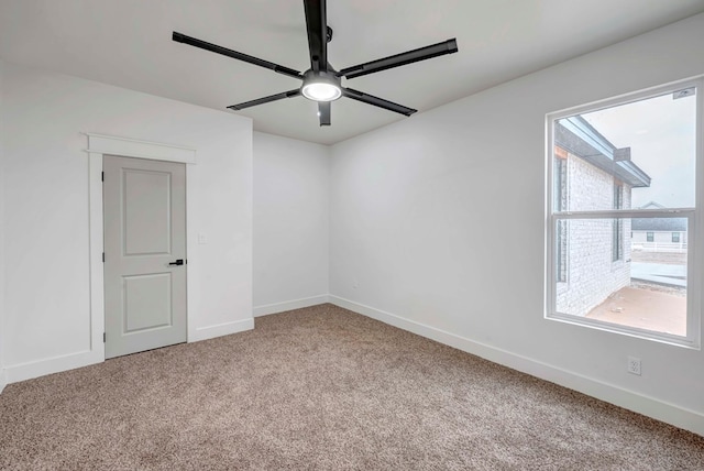 carpeted empty room with a ceiling fan and baseboards