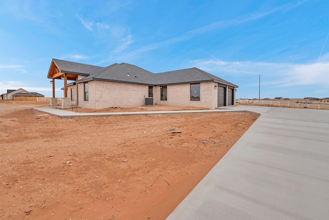 back of property featuring cooling unit, concrete driveway, an attached garage, and fence