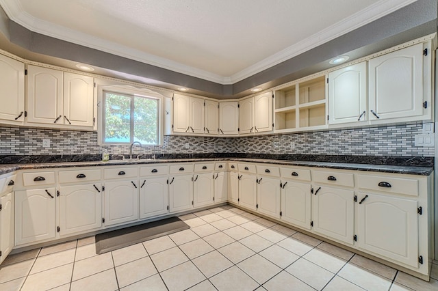 kitchen featuring dark stone countertops, crown molding, light tile patterned floors, sink, and backsplash