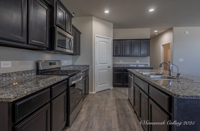 kitchen featuring sink, light hardwood / wood-style flooring, an island with sink, and appliances with stainless steel finishes