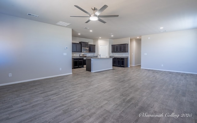 unfurnished living room with dark wood-type flooring, ceiling fan, and sink