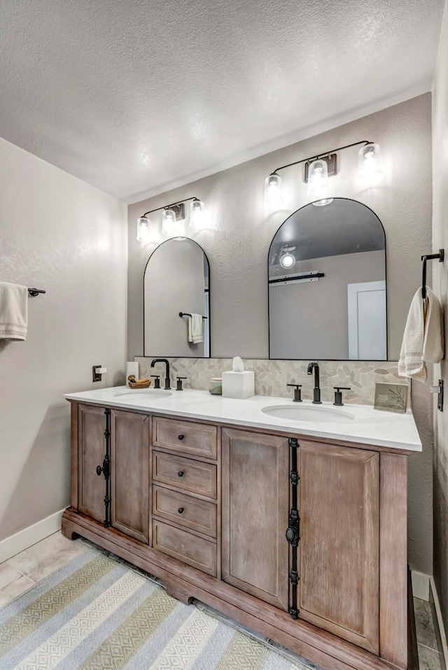 full bathroom with a textured ceiling, double vanity, backsplash, and a sink