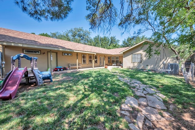 rear view of property featuring a patio area, a yard, and a playground