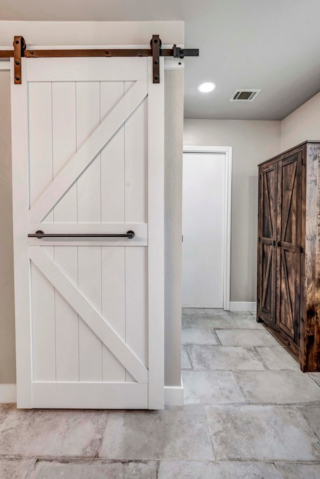 interior space with a barn door, visible vents, baseboards, and recessed lighting