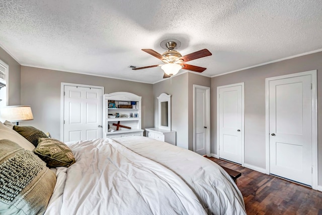 bedroom featuring two closets, ceiling fan, ornamental molding, and dark wood-type flooring