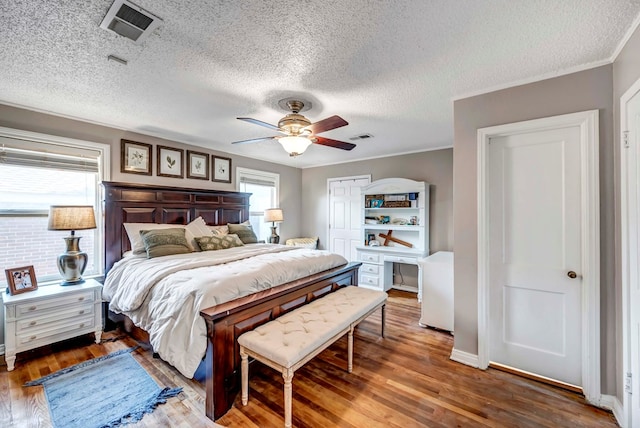 bedroom featuring ornamental molding, dark wood-style flooring, visible vents, and a ceiling fan