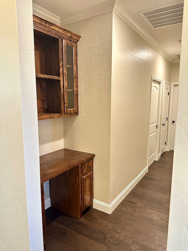 corridor featuring visible vents, dark wood-style floors, crown molding, and a textured wall