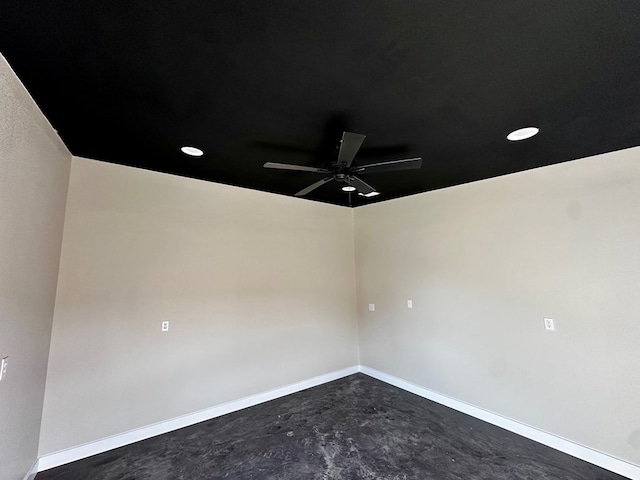 spare room featuring unfinished concrete flooring, a ceiling fan, and baseboards