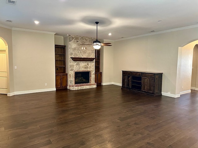 unfurnished living room with arched walkways, dark wood finished floors, a fireplace, and a ceiling fan