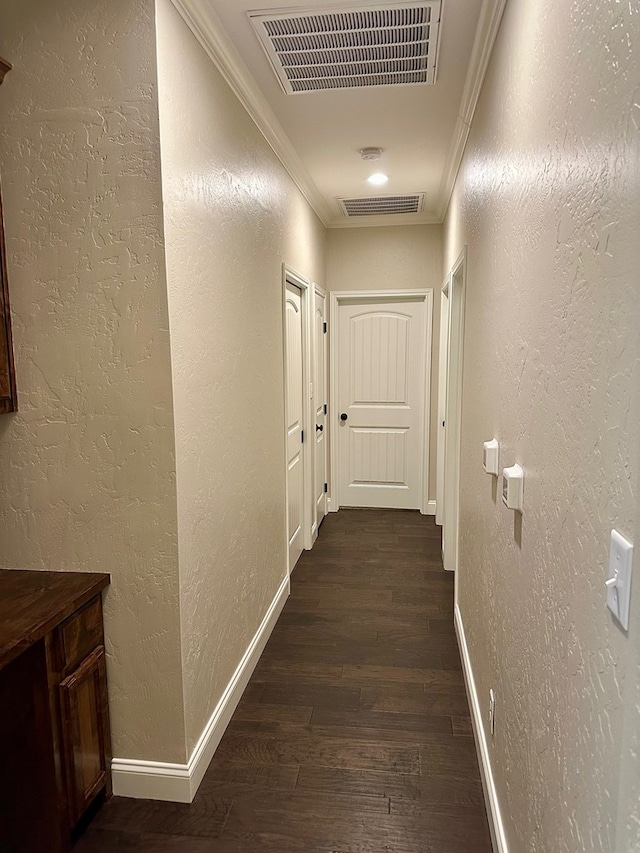 corridor with baseboards, visible vents, ornamental molding, dark wood-type flooring, and a textured wall