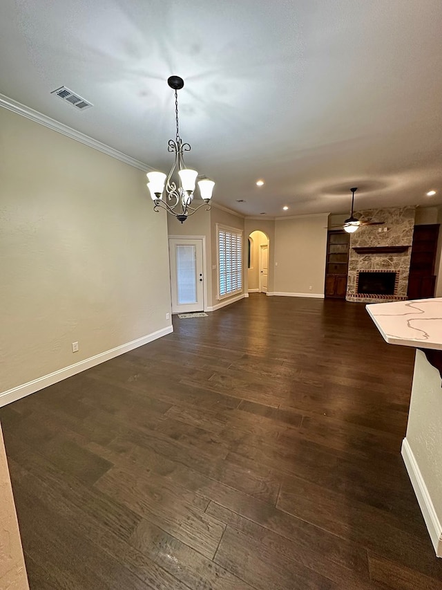 unfurnished living room with visible vents, dark wood finished floors, arched walkways, a fireplace, and crown molding