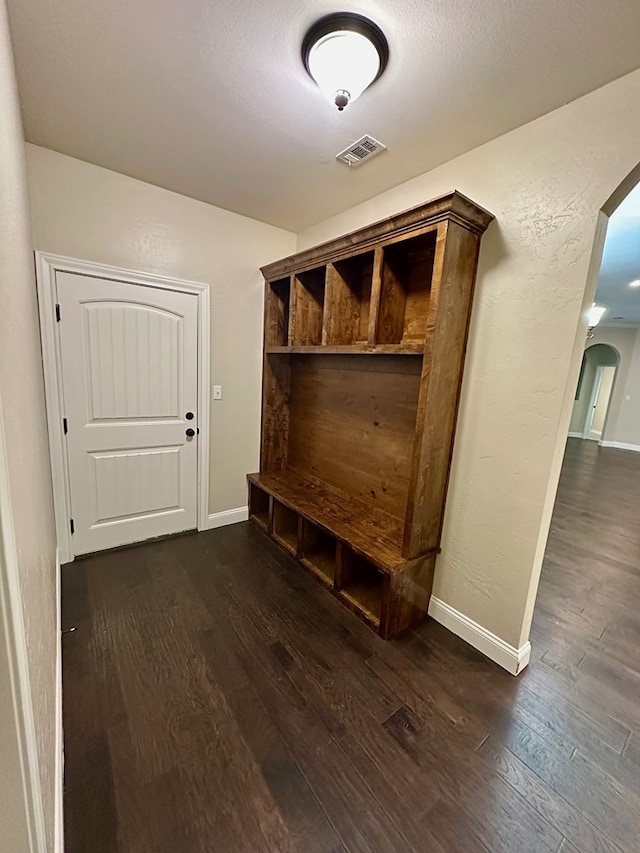 mudroom with visible vents, arched walkways, baseboards, and dark wood-style floors