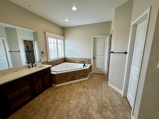 full bath with a stall shower, recessed lighting, a bath, vanity, and a textured wall