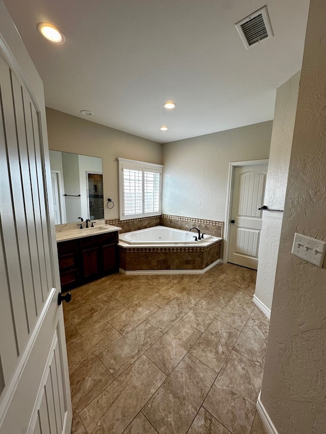 bathroom featuring vanity, visible vents, recessed lighting, a garden tub, and a textured wall