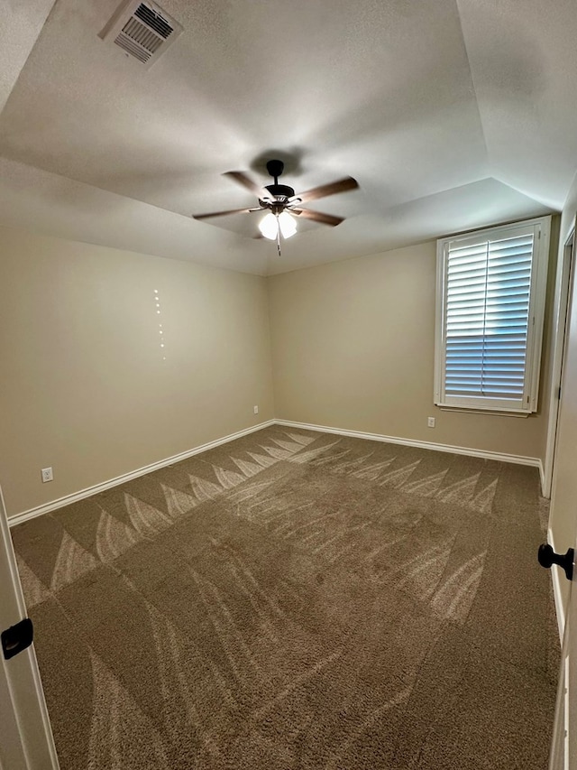 spare room featuring dark colored carpet, visible vents, baseboards, and a ceiling fan