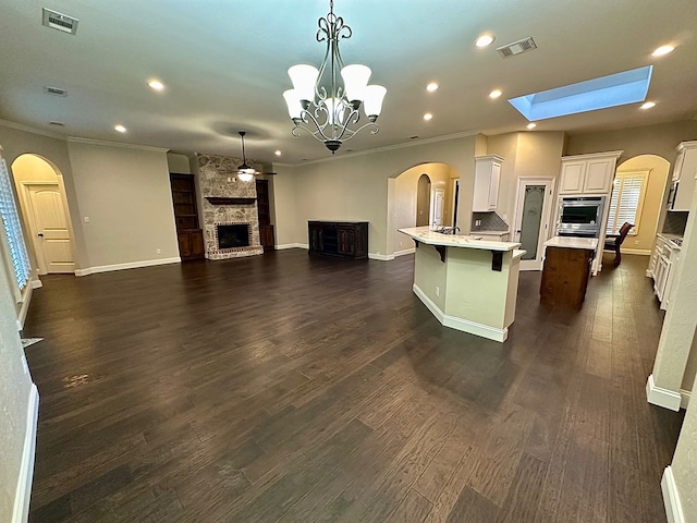 kitchen with open floor plan, a stone fireplace, visible vents, and stainless steel oven