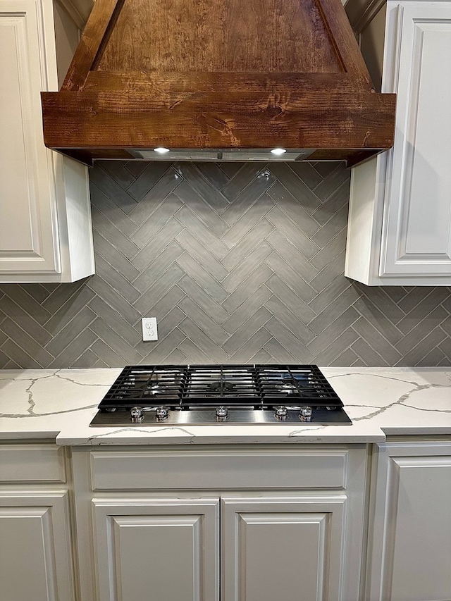 kitchen featuring white cabinets, light stone countertops, tasteful backsplash, and stainless steel gas cooktop