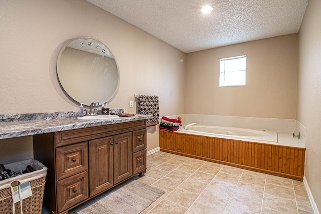 bathroom featuring tile patterned floors, a tub, vanity, and a textured ceiling