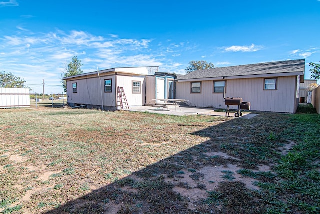 rear view of property featuring an outdoor structure, a patio area, and a yard