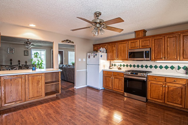 kitchen featuring appliances with stainless steel finishes, dark hardwood / wood-style flooring, backsplash, a textured ceiling, and ceiling fan